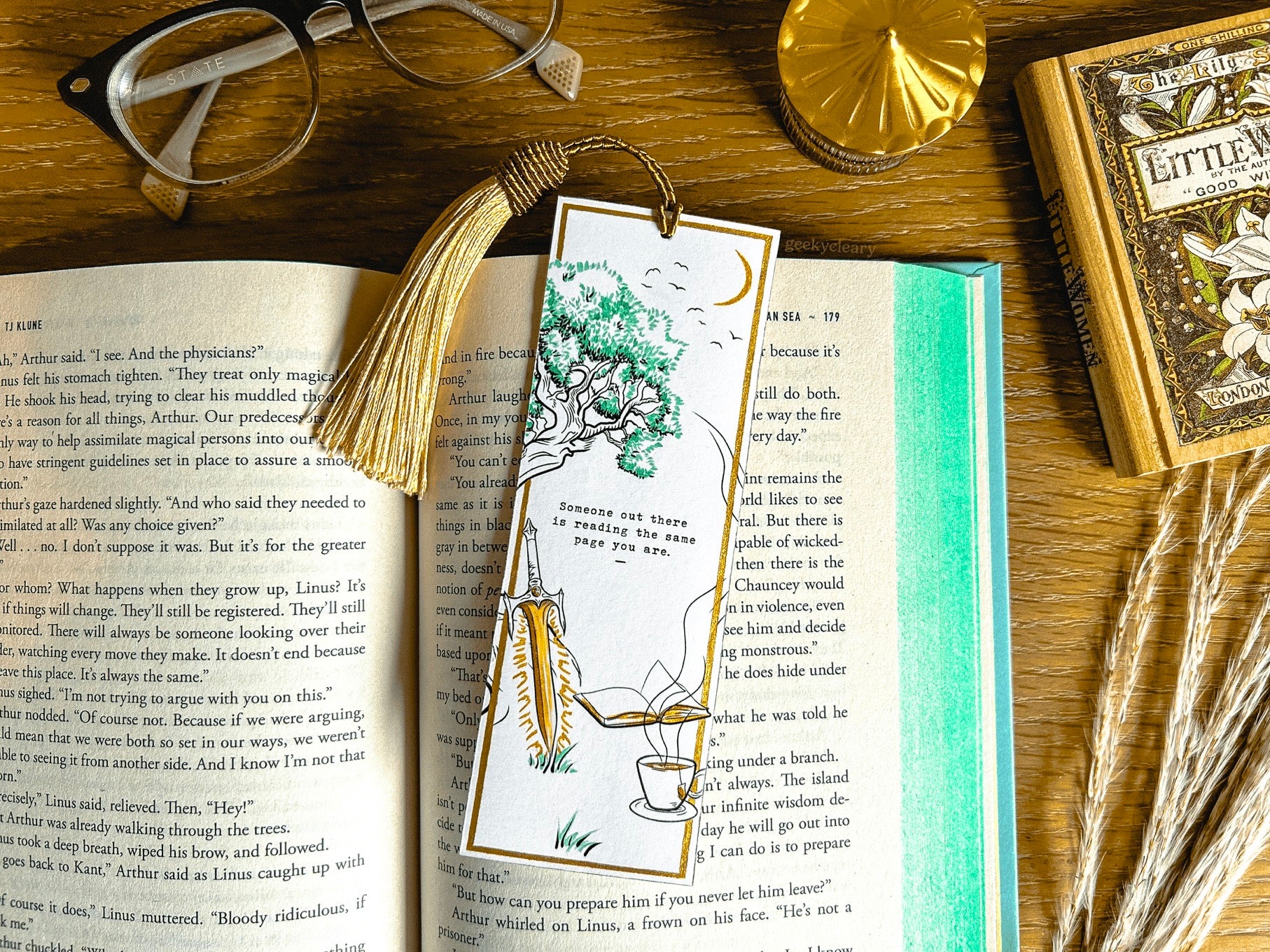 Open hardcover book and a handmade fantasy bookmark featuring the quote "Someone out there is reading the same page you are." Part of our bookish store with handmade book accessories.