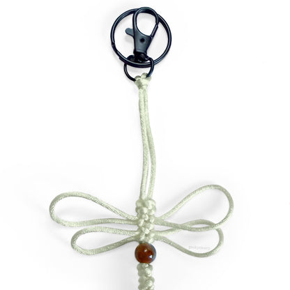 Close up of Bone Relic Dragonfly Specimen keychain made of off-white silk cord, a real agate bead, and black-toned hardware.