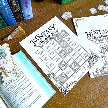 Fantasy book bingo sheets on a wooden table with game cards, gem pieces, and books.
