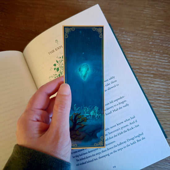 Floating Crystalized Magic bookmark - hand marking a page in a hardback fantasy book.