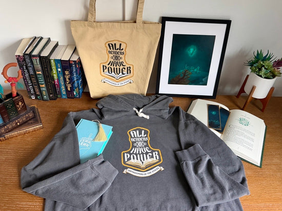Close up of All Readers Have Power hoodie and tote styled with Floating Crystalized Magic art print, fantasy bookmarks details.